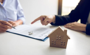 Sigorta komisyoncuları sigorta kontratının imzalandığına işaret ediyor ve ofisteki müşterilere açıklıyorlar..