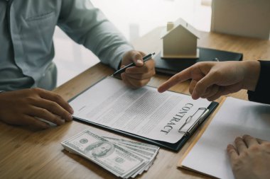 Sigorta komisyoncuları sigorta kontratının imzalandığına işaret ediyor ve ofisteki müşterilere açıklıyorlar..