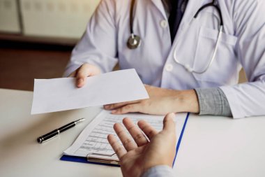 Asyalı erkek doktor klinikte konuşuyor ve hastaya reçete veriyor..