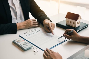 Sigorta komisyoncuları sigorta kontratının imzalandığına işaret ediyor ve ofisteki müşterilere açıklıyorlar..