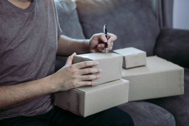 Genç Asyalı adam sahibi eller iş adresi işyeri veya ev ofis, karton kutu üzerinde yazma.