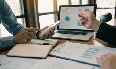 Ofis odasındaki bütçe toplantısında finansal planlama grafiği ve şirket bütçesini tartışan iki iş ortağı analiz stratejisi.