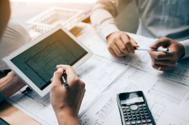 İki mühendislik birlikte çalışan ve dijital tablet seyir planı ve analiz mimari plan üstünde okul sırası ile kullanma.