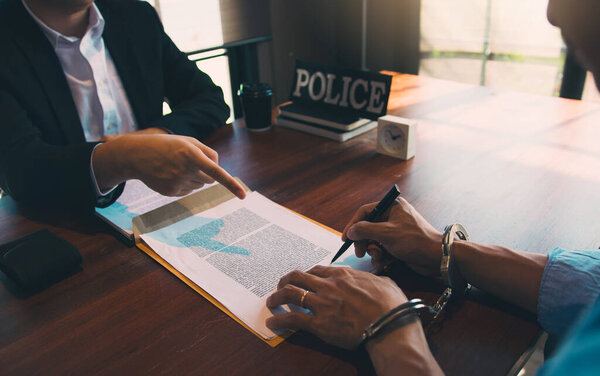 Полиция указала на документ, чтобы подозреваемый подписал заявление и надел наручники на арест..