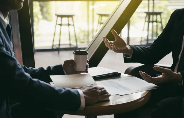 Two business partnership coworkers analysis cost work progress and gesturing with discussing a financial planning graph and company financial during a budget meeting in office room.