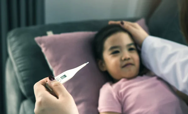 Asian female pediatrician is using a thermometer to measure fever for children
