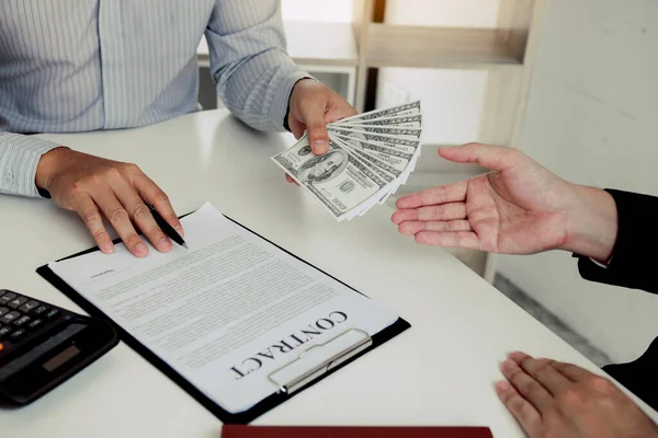 腐敗の概念に関する契約書の署名を強制するために起業家に提出しているビジネスマンの手にお金 — ストック写真