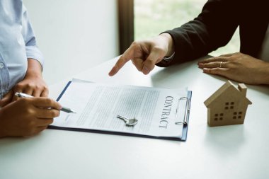 Sigorta komisyoncuları sigorta kontratının imzalandığına işaret ediyor ve ofisteki müşterilere açıklıyorlar..