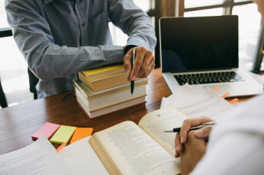 Gençler masa başında çalışıyor ve ödevlerini yapıyor.