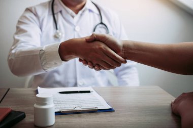 Doktor klinikteki yaşlı hastayla el sıkışıyor..