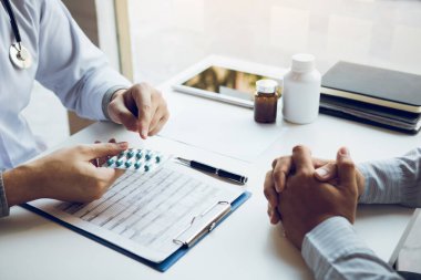 Doktor, ofisteki tümörlerin tedavisi için ilaç kullanımına ilişkin tavsiyelerde bulunmak üzere bir ilaç paneli tutuyor..