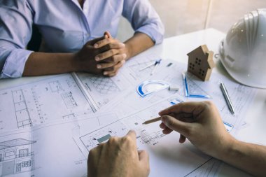 Ofisteki meslektaşımla yeni projeyi tartışmak için plan üzerinde çalışan mimar.