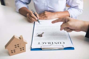 Sigorta komisyoncuları sigorta kontratının imzalandığına işaret ediyor ve ofisteki müşterilere açıklıyorlar..