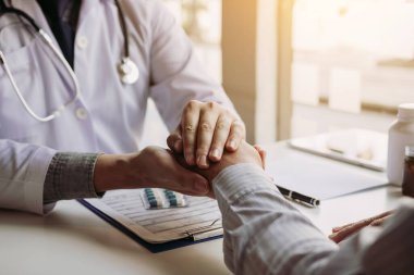 Doktor hastanın elini tutuyor ve hastalığın semptomlarını tedavi etmek için umut veriyor..