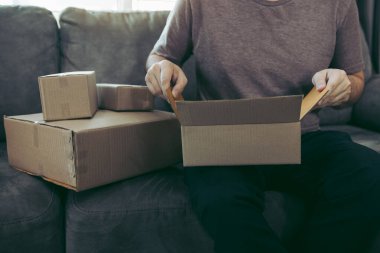 Asyalı girişimci ergen müşterinin sipariş ettiği ürünü kutuya koymak için bir karton kutu açıyor..