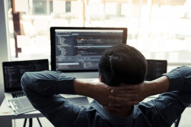 Asyalı programcılar dinleniyor ve ofisteki bilgisayar ekranındaki koda bakıyorlar..