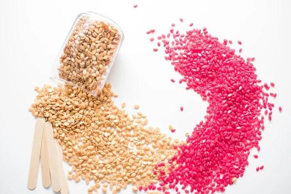 Kırmızı ve altın renkli granüller cam bir kavanozdan dökülen beyaz arka planda izole edilmiş..