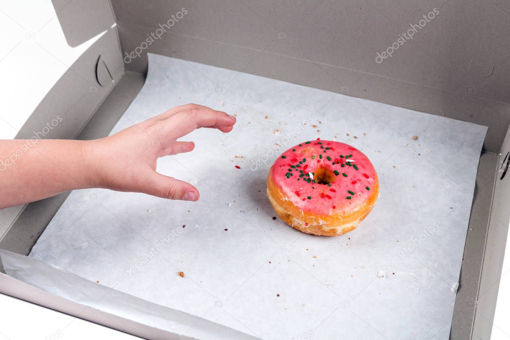 Child stealing the last donut from the box