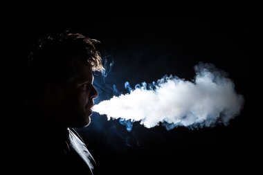 Karanlık, arkadan aydınlatmalı bir adam vaping profil görünümü