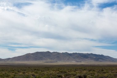 Güzel beyaz bulutlar canlı mavi gökyüzüne ve alçak sıradağlara karşı