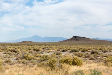 Bulutlu mavi gökyüzü ile kaplı sagebrush ve çöl