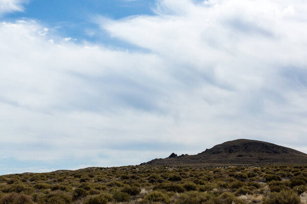 Sagebrush and desert capped by cloudy blue skies