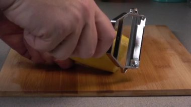 Slicing a yellow summer squash into strips with a julienne peeler.