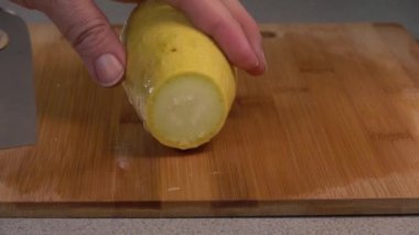 Slicing a yellow summer squash with a cleaver