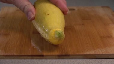 Slicing yellow summer squash on a wood cutting board