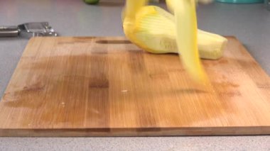 Dropping thin slices of yellow summer squash onto a cutting board