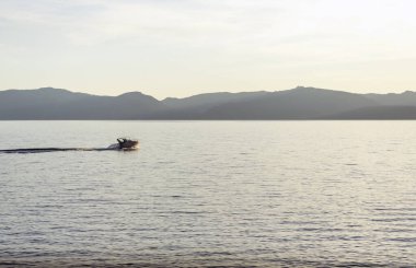 Sürat teknesi gün batımında Tahoe gölünde dalgalar yaratıyor.