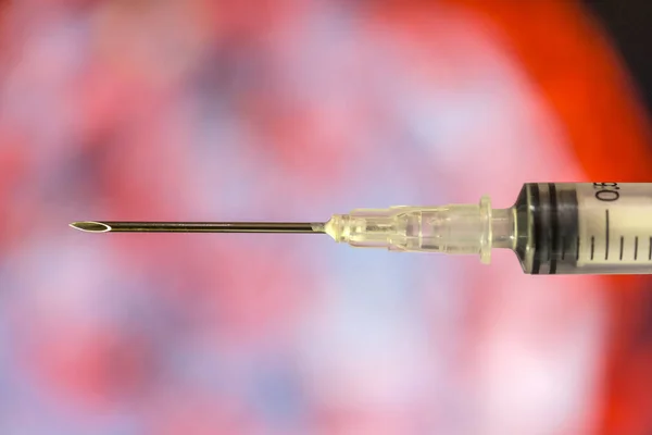 Hypodermic needle  over a red black and grey out of focus background