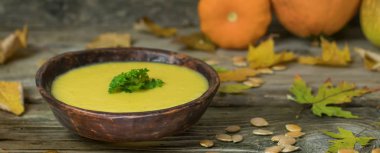 Kış kabak krem çorba el içinde sonbahar akçaağaç yaprakları ve küçük squash rustik eski ahşap zemin üzerine seramik tabak hazırladım. Vegan beslenme gıda.