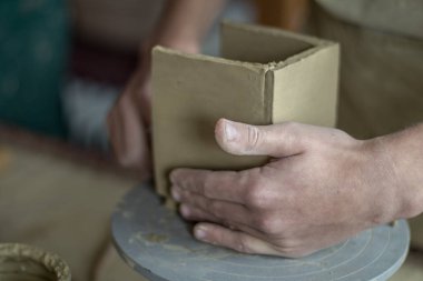 Genç erkek ile kil çömlek atölyesinde çalışan ana potter. Önden Görünümü kapatın. Sanat ve iş, hobi ve serbest çalışma kavramı. Seçici odak.