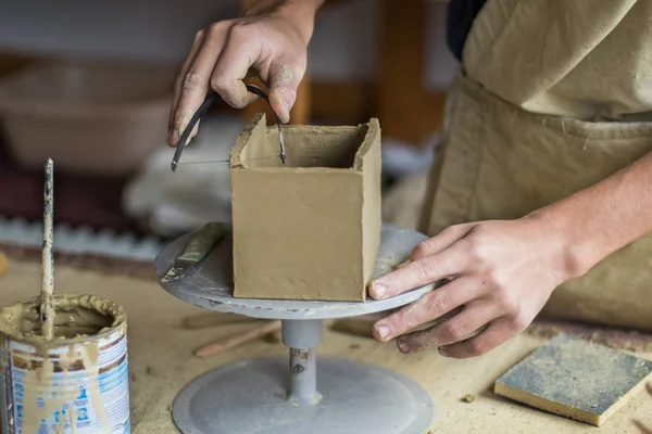 Unga manliga potter master arbetar med lera i keramikverkstaden. Framifrån närbild. Konst och företag, hobby och frilansande arbetande begreppen. Selectiva fokus. Stockbild