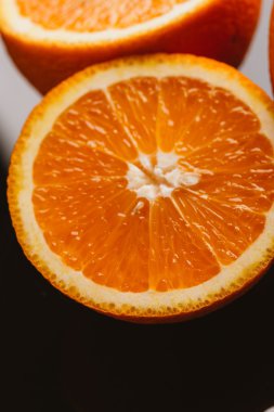 dilimlenmiş portakal yarısı ve bütün koyu arka planı portre üzerinde