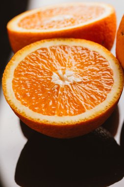 dilimlenmiş portakal yarısı ve bütün koyu arka planı portre üzerinde
