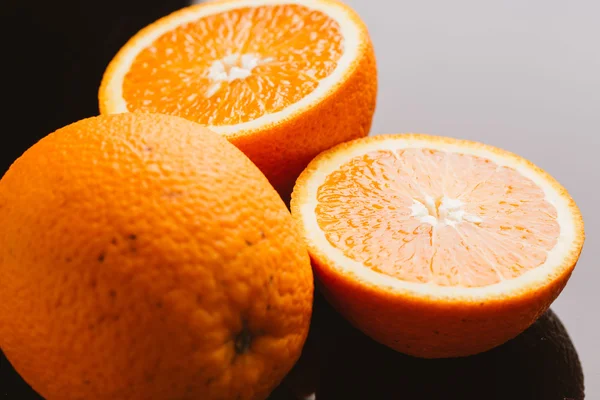 dilimlenmiş portakal yarısı ve bütün koyu arka planı portre üzerinde