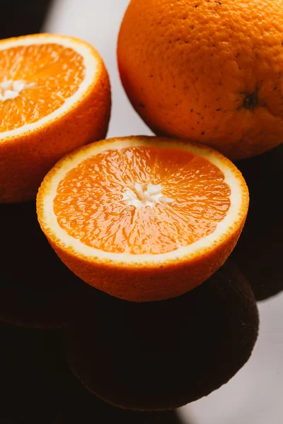 dilimlenmiş portakal yarısı ve bütün koyu arka planı portre üzerinde