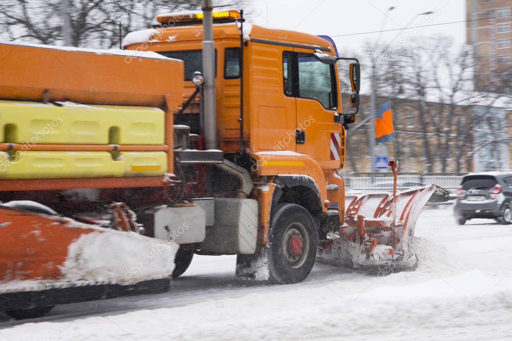 the snow-removing machine works on a snow-covered road. photo a little blurry in motion