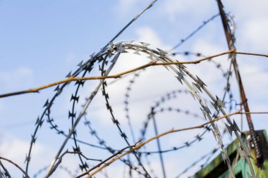 Çitin dikenli telleri yakın plan. Dikenli tellerin arasından gökyüzü. resim özgürlüğün, tehlikenin, gri nesnelerin kısıtlanmasını simgeliyor.