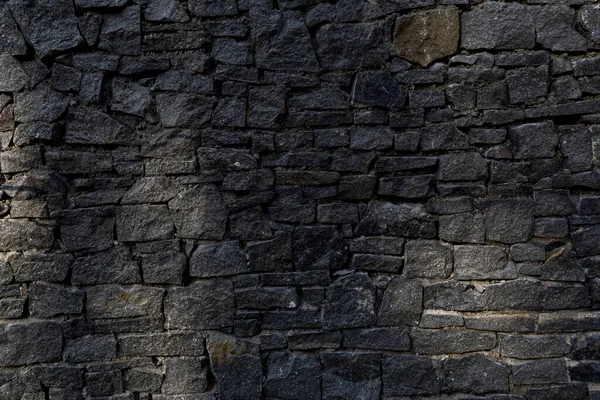 stone fence. fence of black stones of irregular shape. a fence of chipped stones. stone texture.
