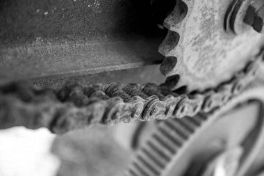 Eski terk edilmiş arabaların paslı detayları. Vitesler, zincirler, makaralar açıkta paslanıyor. Tarım makinelerinin yosun kaplı metal parçaları. Siyah ve beyaz resim.