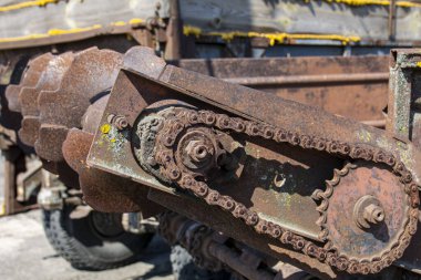Eski terk edilmiş arabaların paslı detayları. Vitesler, zincirler, makaralar açıkta paslanıyor. Tarım makinelerinin yosun kaplı metal parçaları.