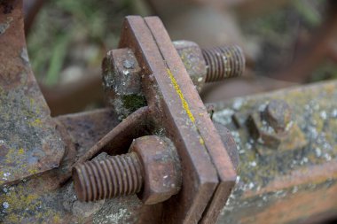 Eski terk edilmiş arabaların paslı detayları. Vitesler, zincirler, makaralar açıkta paslanıyor. Tarım makinelerinin yosun kaplı metal parçaları.