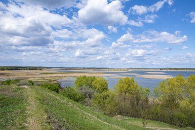 Güzel manzara. Bulutlu mavi gökyüzü, tepeden göle manzara, çevrede yeşil ağaçlar. Bahar güneşli gün.