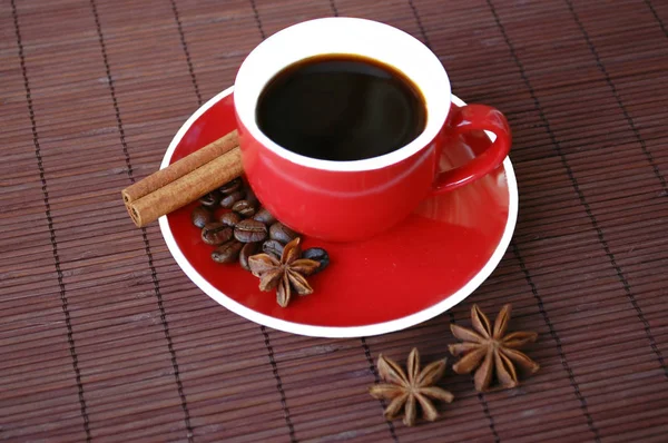 Rote Tasse schwarzen Kaffee. Zimtstangen und Anis-Sterne. — Stockfoto