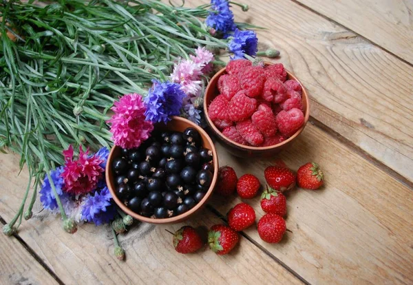 Two bowls with berries and a bouquet of flowers — Stock Photo, Image