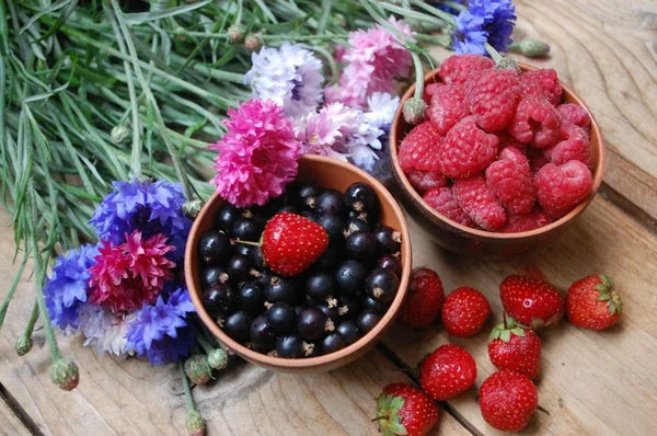 Две чаши с ягодами и букет цветов — стоковое фото