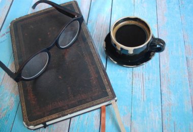 kitap, gözlük ve küçük bir fincan mavi bir arka plan üzerinde siyah kahve